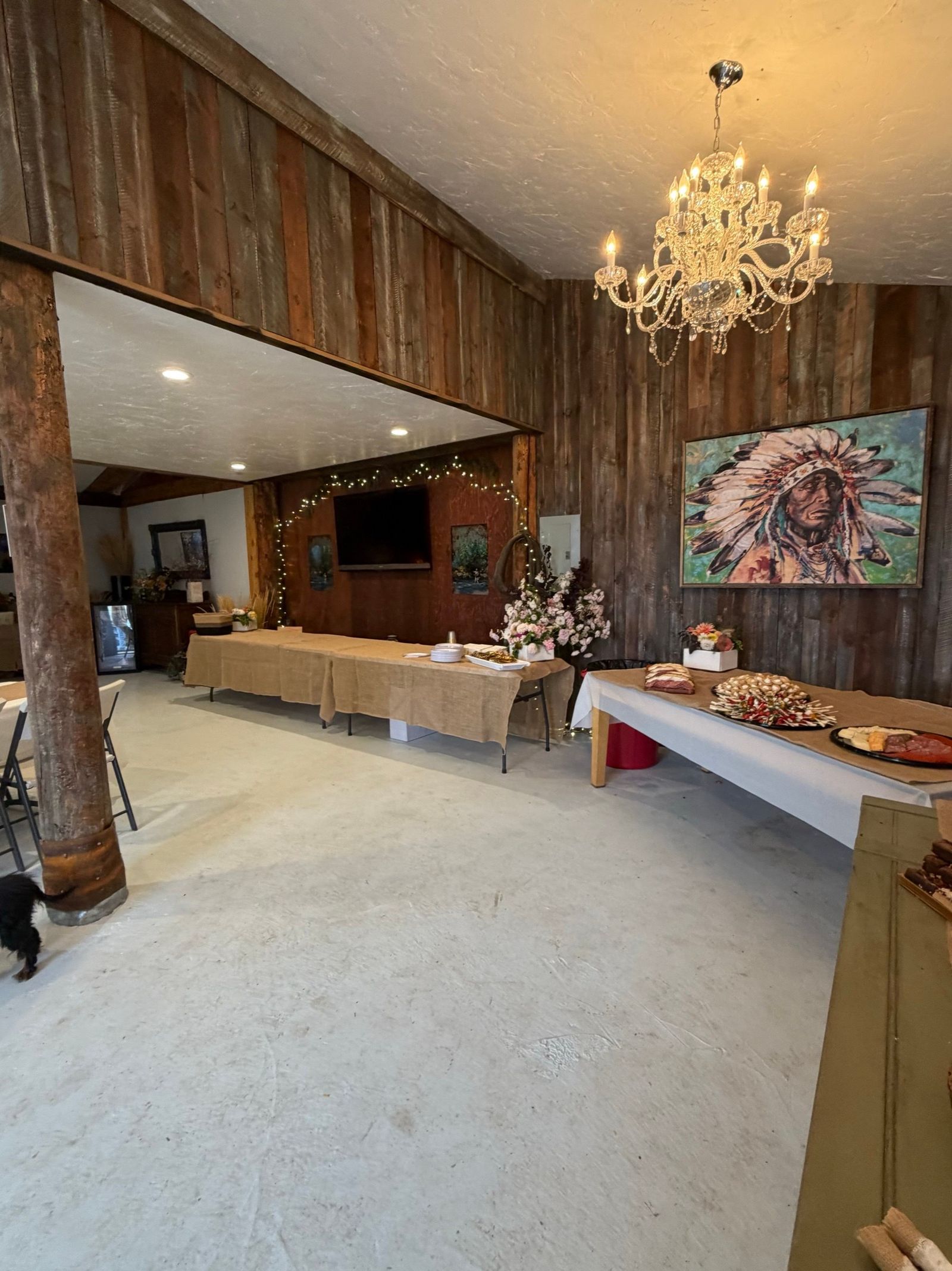 Inside the Bourbon Barn set for a reception - a crystal chandelier, reclaimed-wood walls, and the painted chief above the buffet