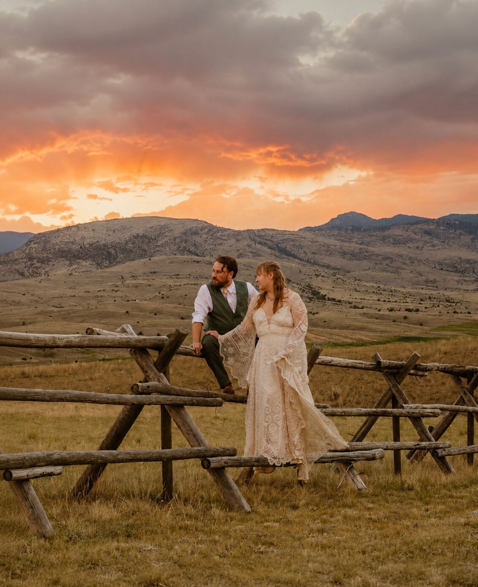 A couple on the jackleg fence at sunset, the sky burning orange over the mountains