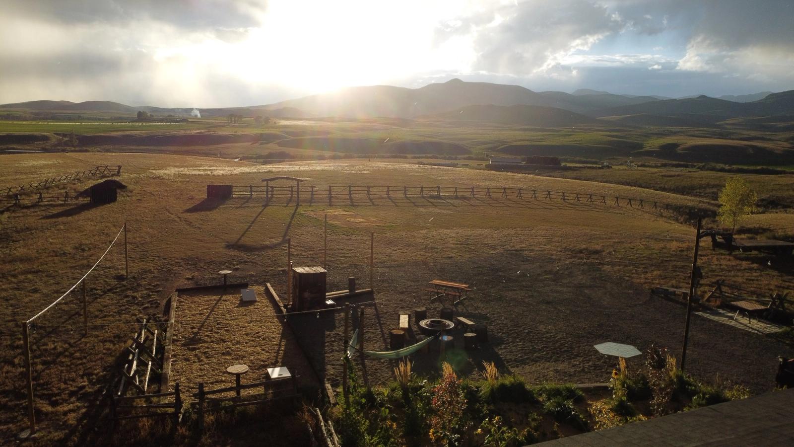 Late sun breaking over the valley above the farm's camping area, fire ring, and hammock