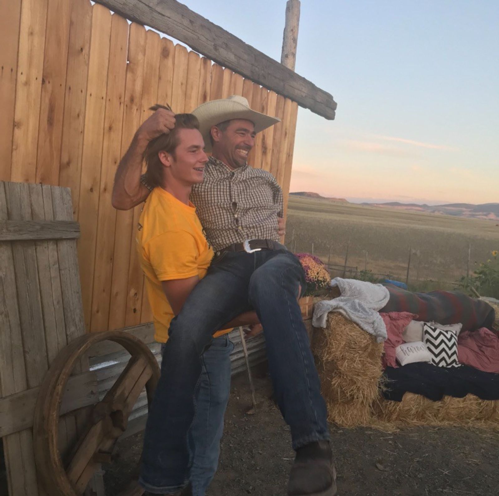 Two guests clowning for the camera beside a hay-bale lounge at sunset