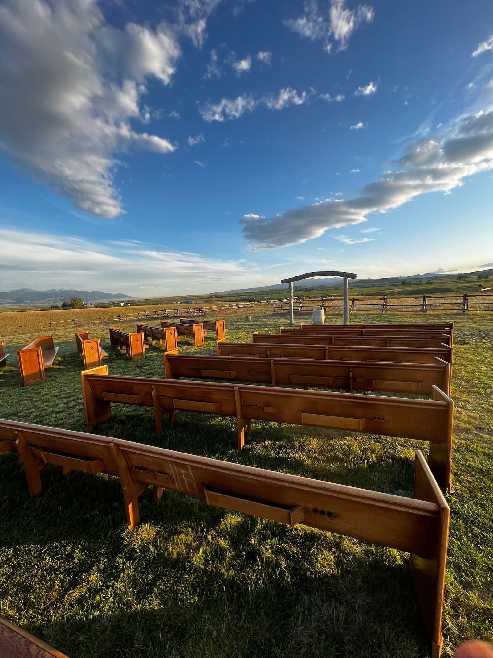 The handcrafted pews seen from the front row, blue sky and mountains beyond