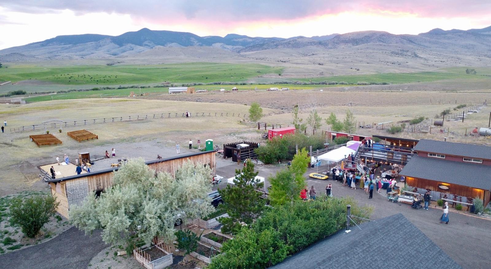 A celebration at GardenMontana from above at sunset - the ceremony benches, the Bourbon Barn, and the valley and mountains beyond
