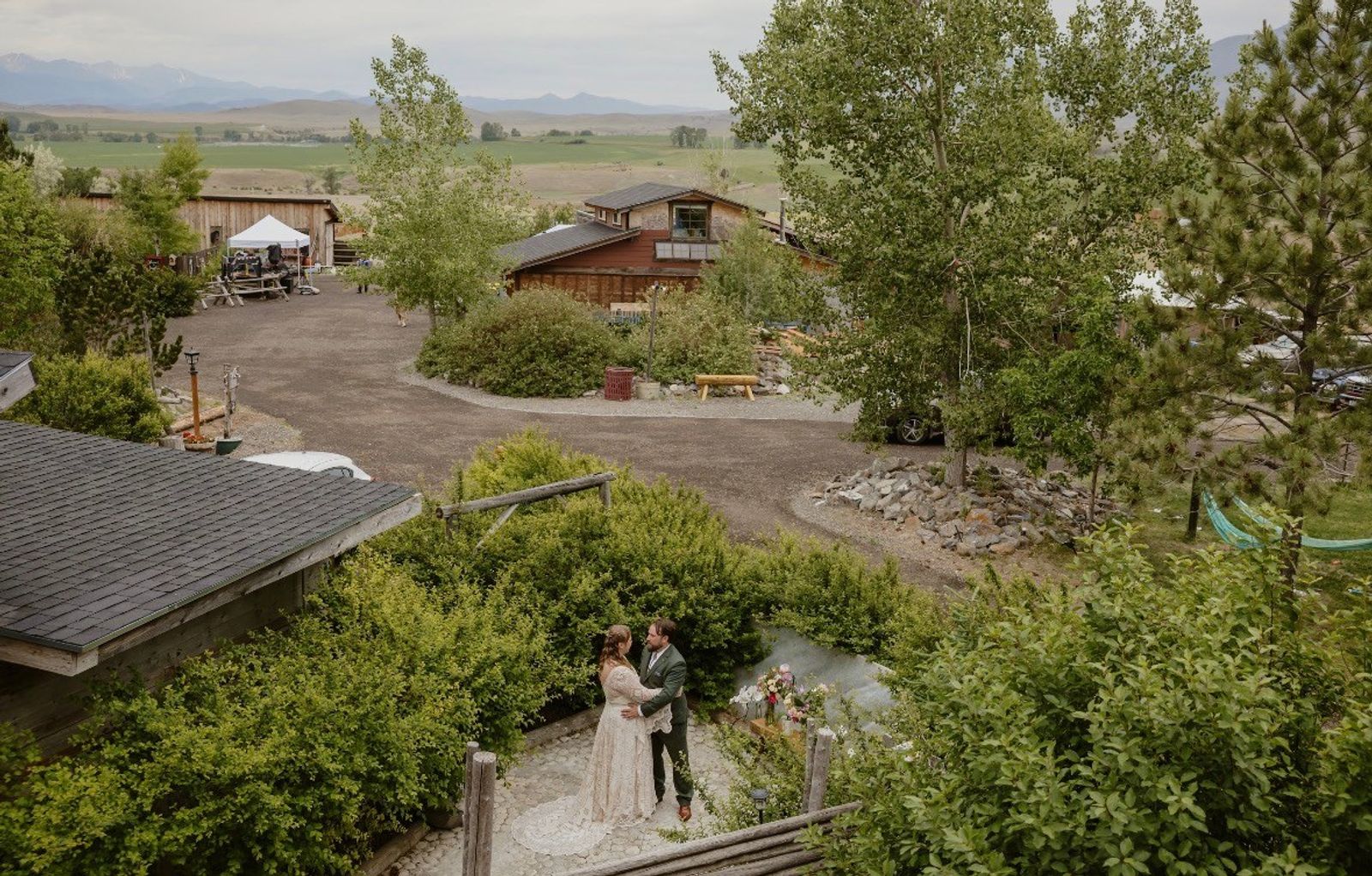 A couple sharing a quiet moment on the stone path below, the farm and valley stretching out behind them