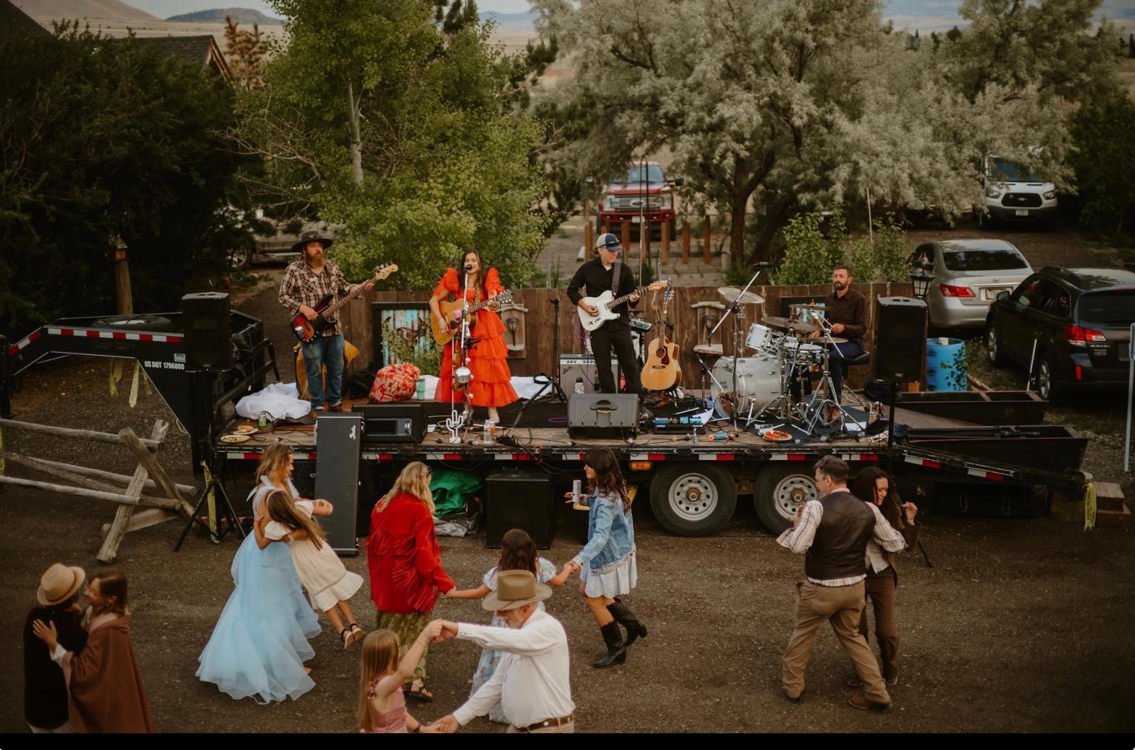 A live band on a flatbed stage while guests of every age dance in the yard