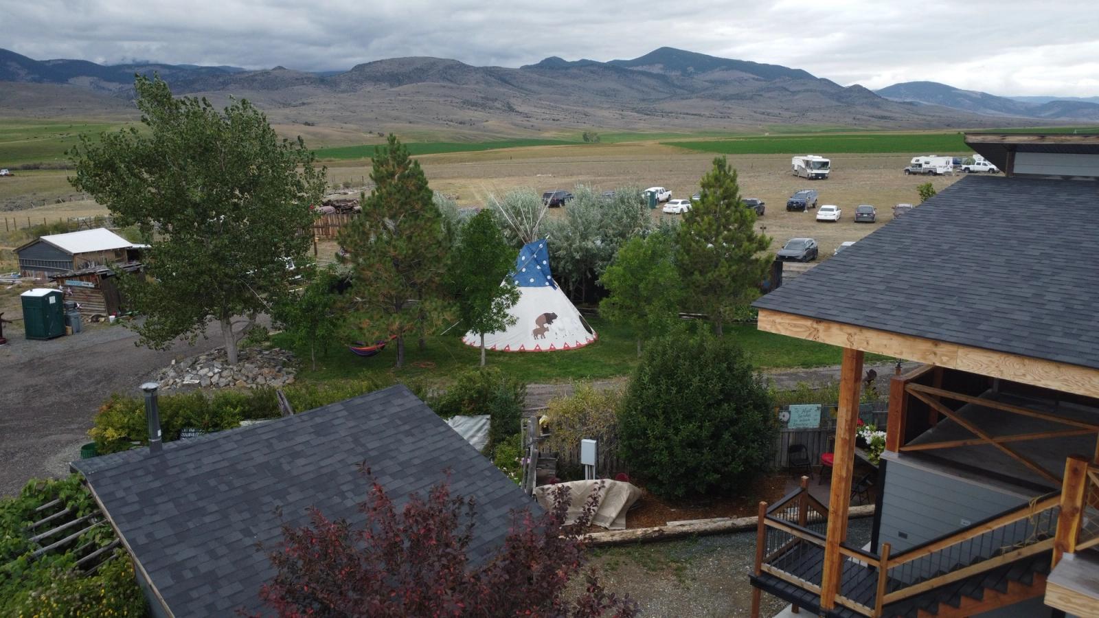 The farm from above - the tipi among the trees, the deck in the foreground, and the valley and mountains beyond