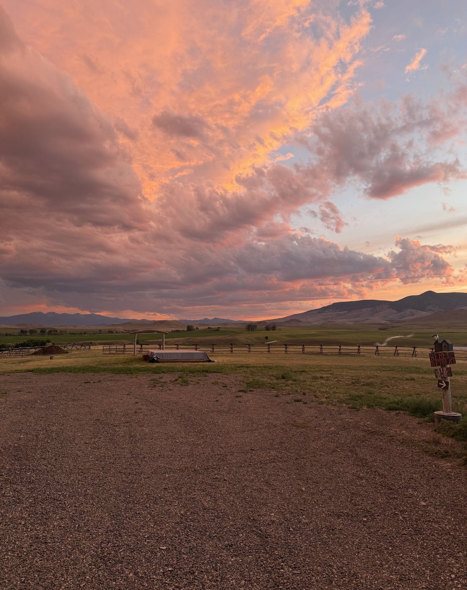 A pink and orange sunset blazing over the meadow and the farm lane
