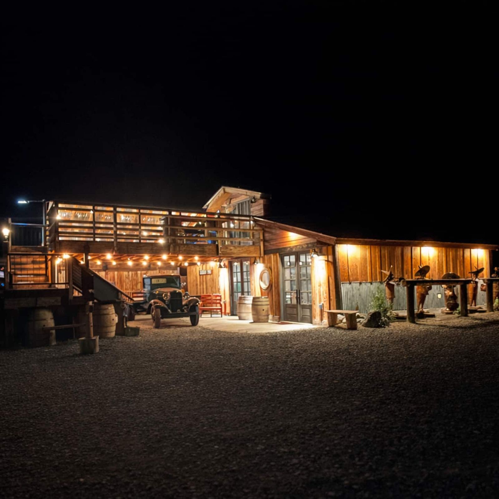The Bourbon Barn lit up at night, string lights glowing along the deck