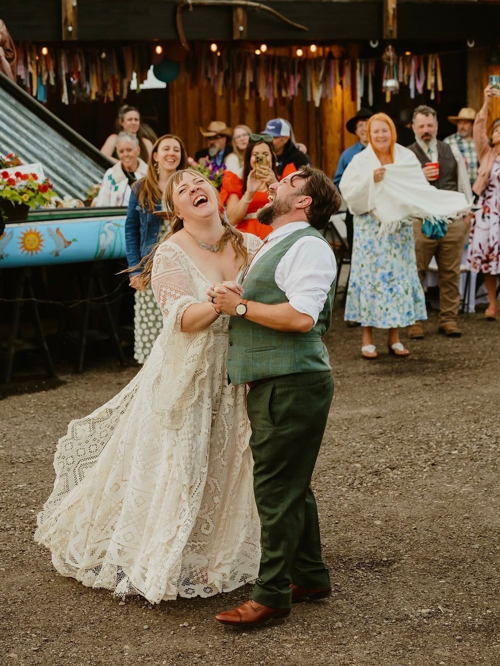 Newlyweds laughing through their first dance while friends and family cheer them on