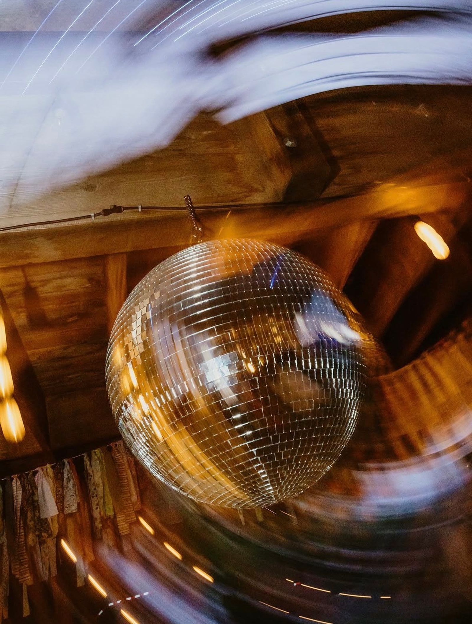 A disco ball spinning under the Bourbon Barn rafters, light trailing around it