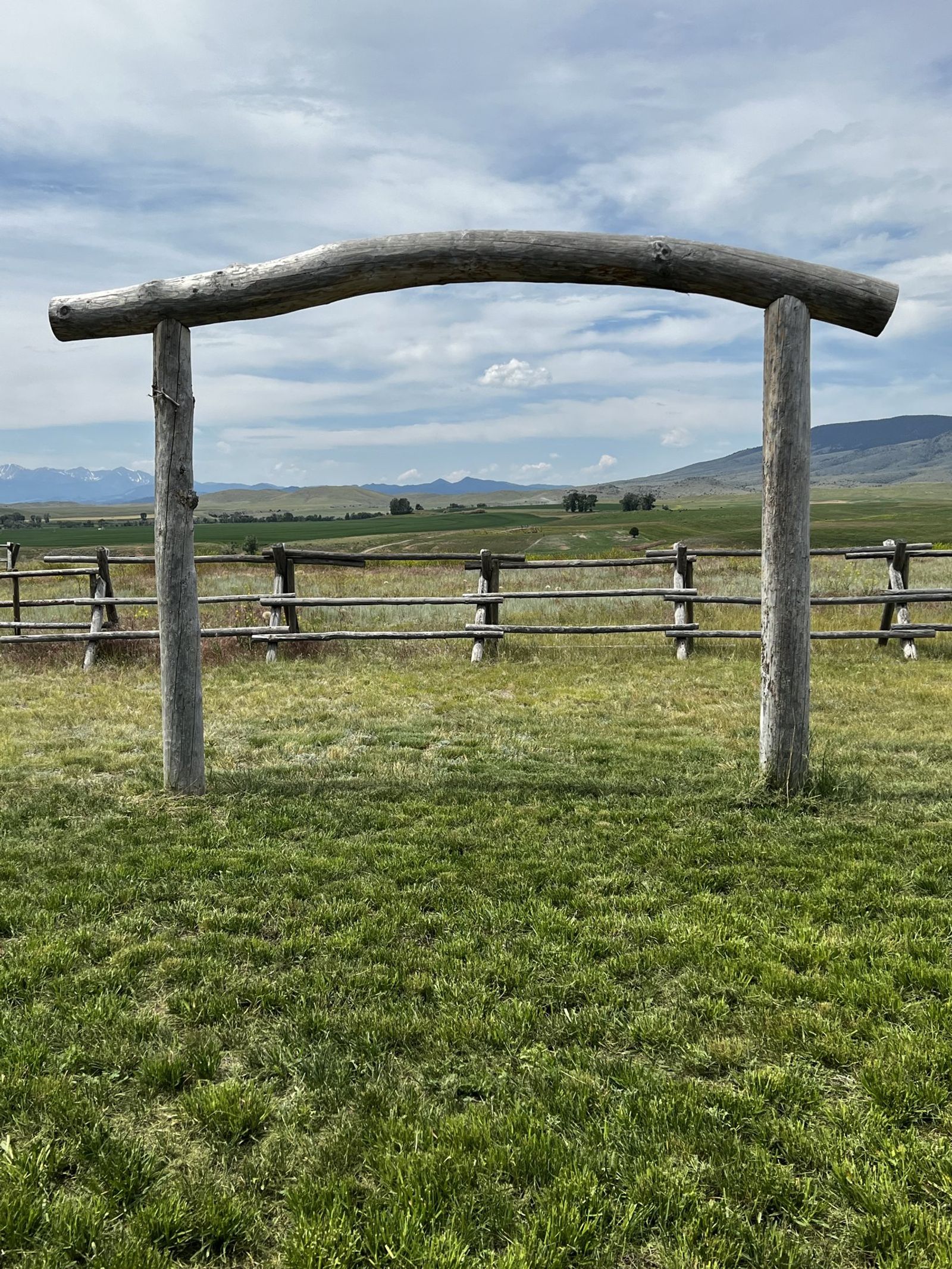 The log ceremony arch in the meadow, the jackleg fence and the valley behind it