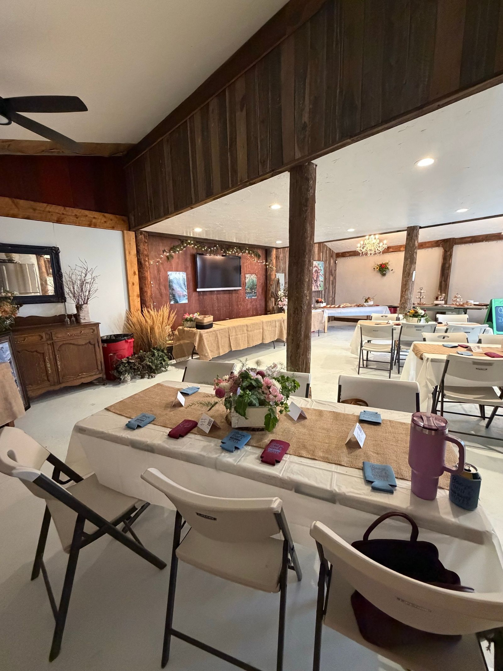 A long table set inside the Bourbon Barn - burlap runner, farm bouquet, and napkins at every place, the chandelier beyond