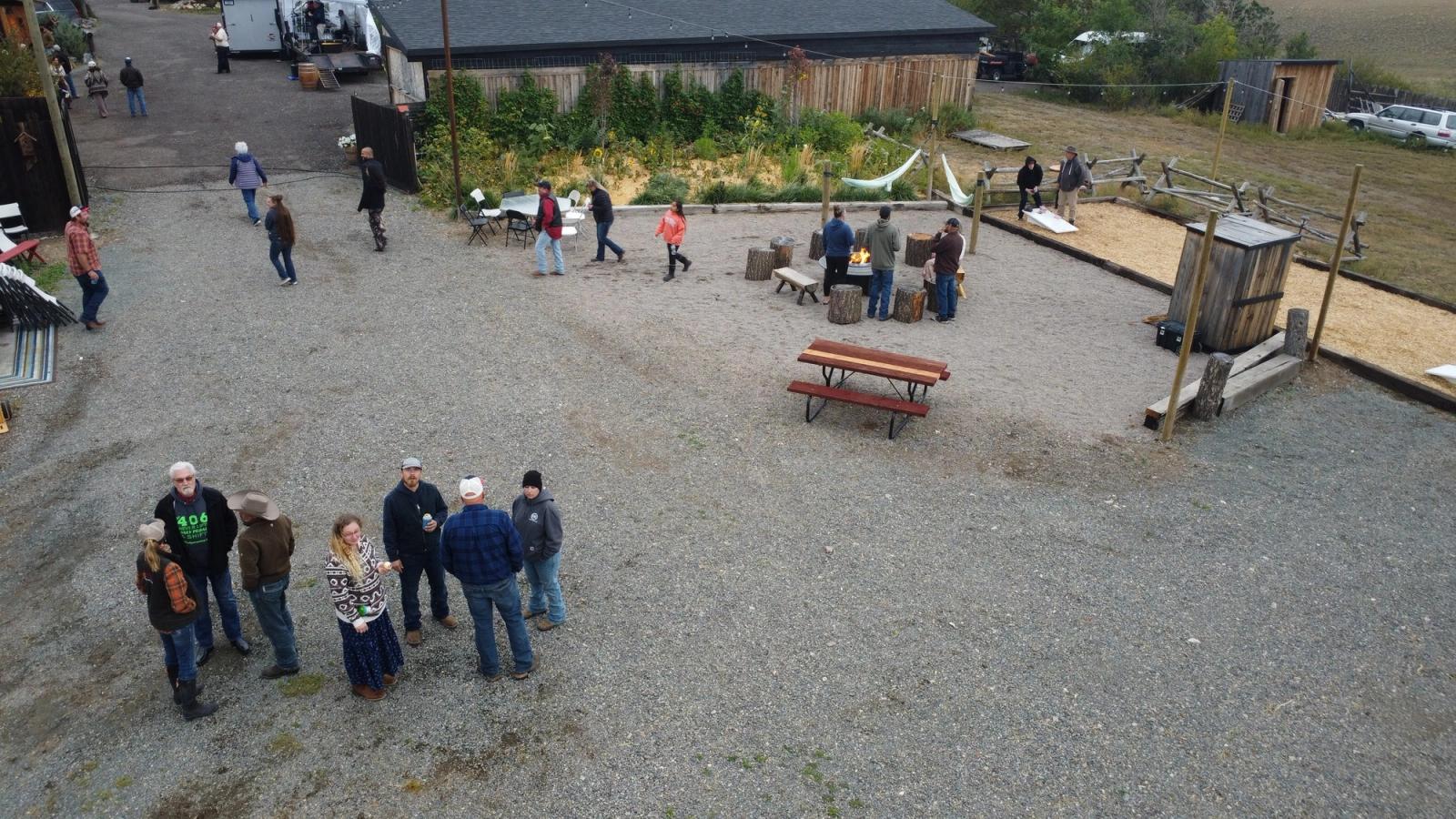 Guests gathered around the fire pit and picnic tables, seen from above