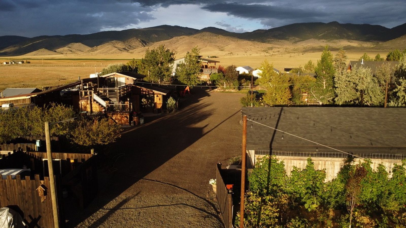The gravel lane into the farm at golden hour, the Bourbon Barn on the left and storm light over the mountains