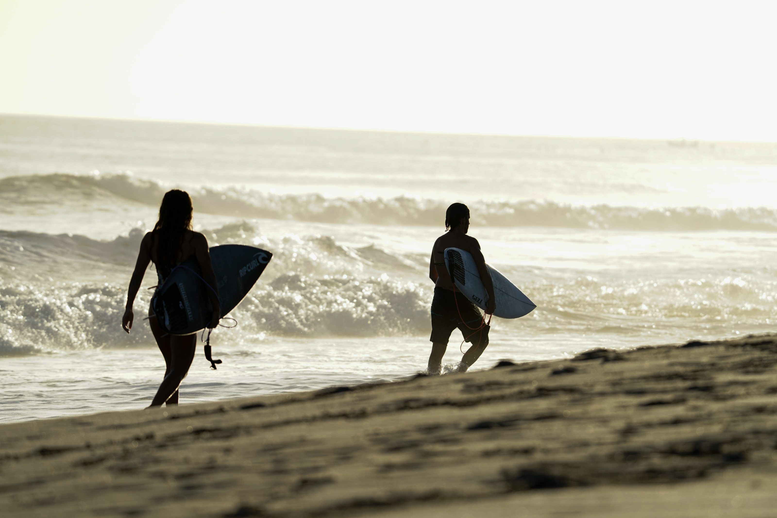Dos surfistas con sus tablas caminando por la orilla al atardecer en Nicaragua