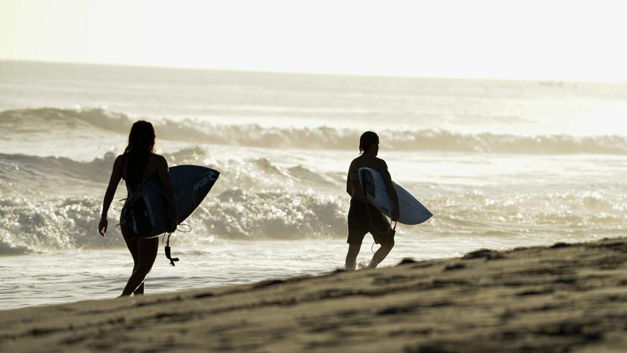 Dos surfistas con sus tablas caminando por la orilla al atardecer en Nicaragua