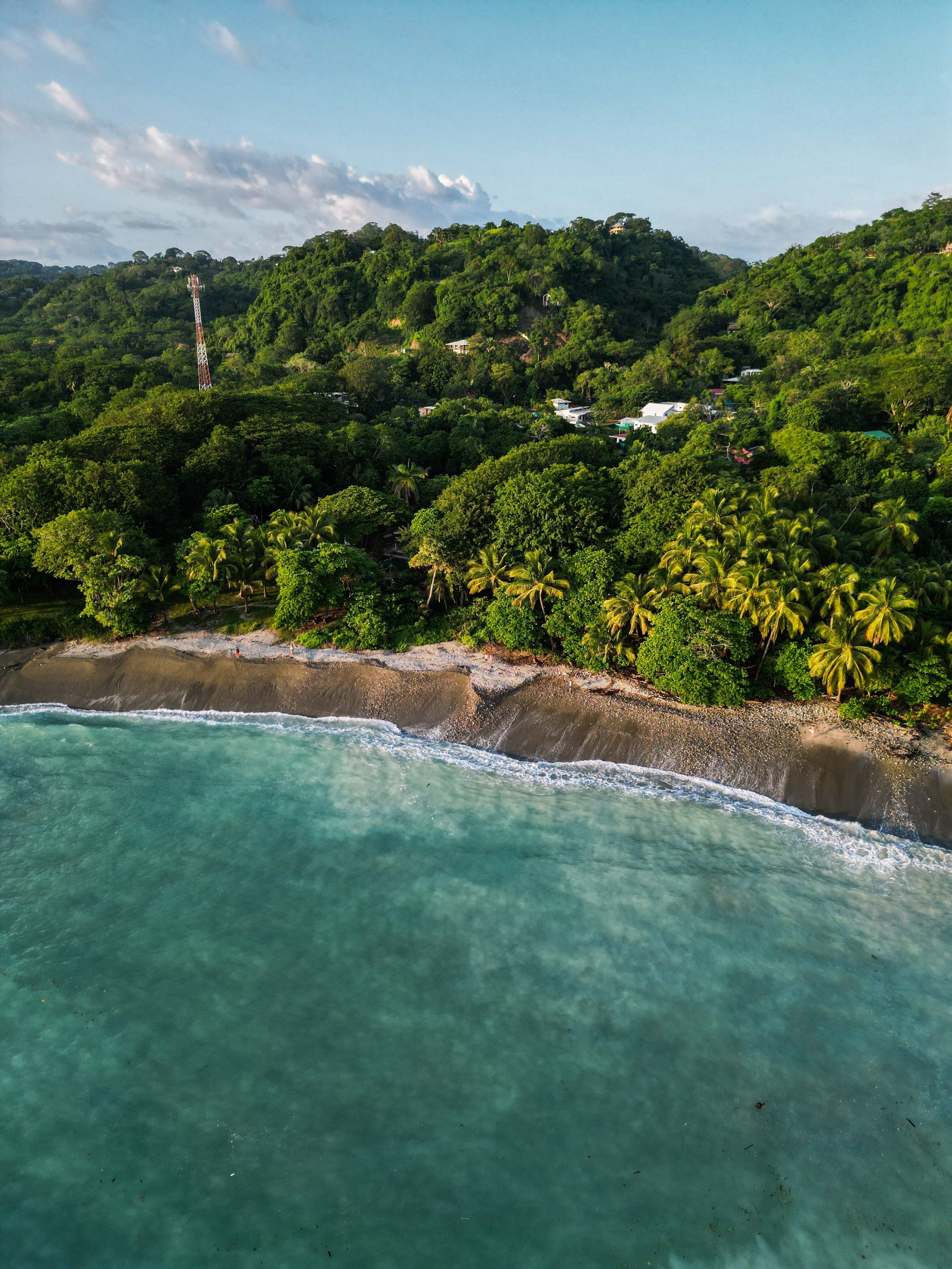Vista aérea de una costa de Costa Rica con selva tropical, palmeras y una playa de agua turquesa