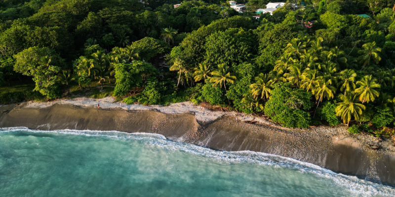 Vista aérea de una caleta en Costa Rica: agua turquesa, rocas y selva junto a la playa