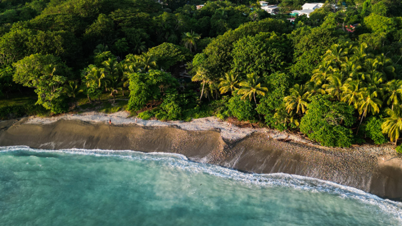 Vista aérea de una caleta en Costa Rica: agua turquesa, rocas y selva junto a la playa