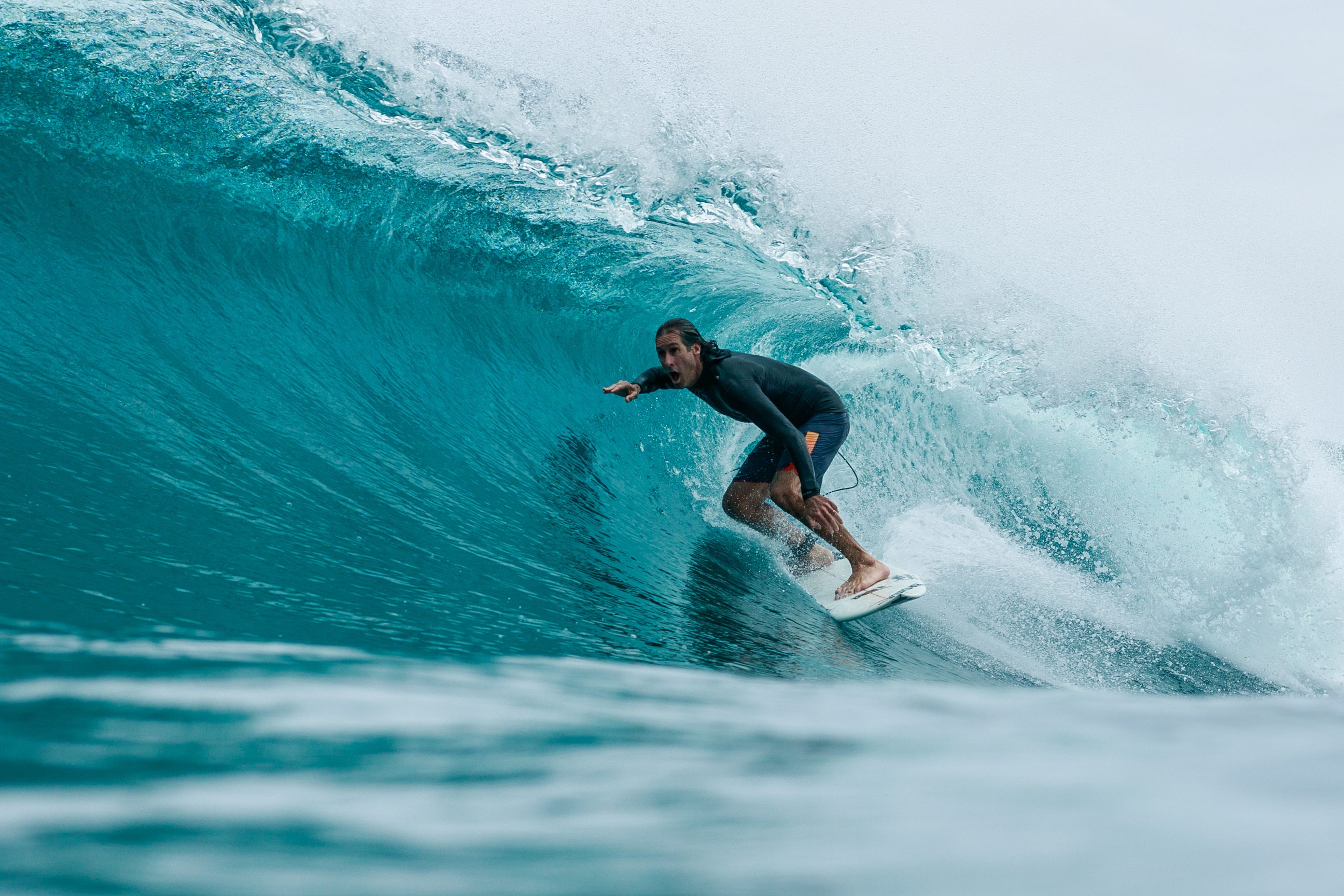 Surfista dentro de un tubo turquesa en Maldivas
