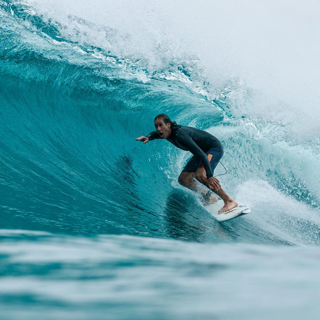 Surfista dentro de un tubo turquesa en Maldivas