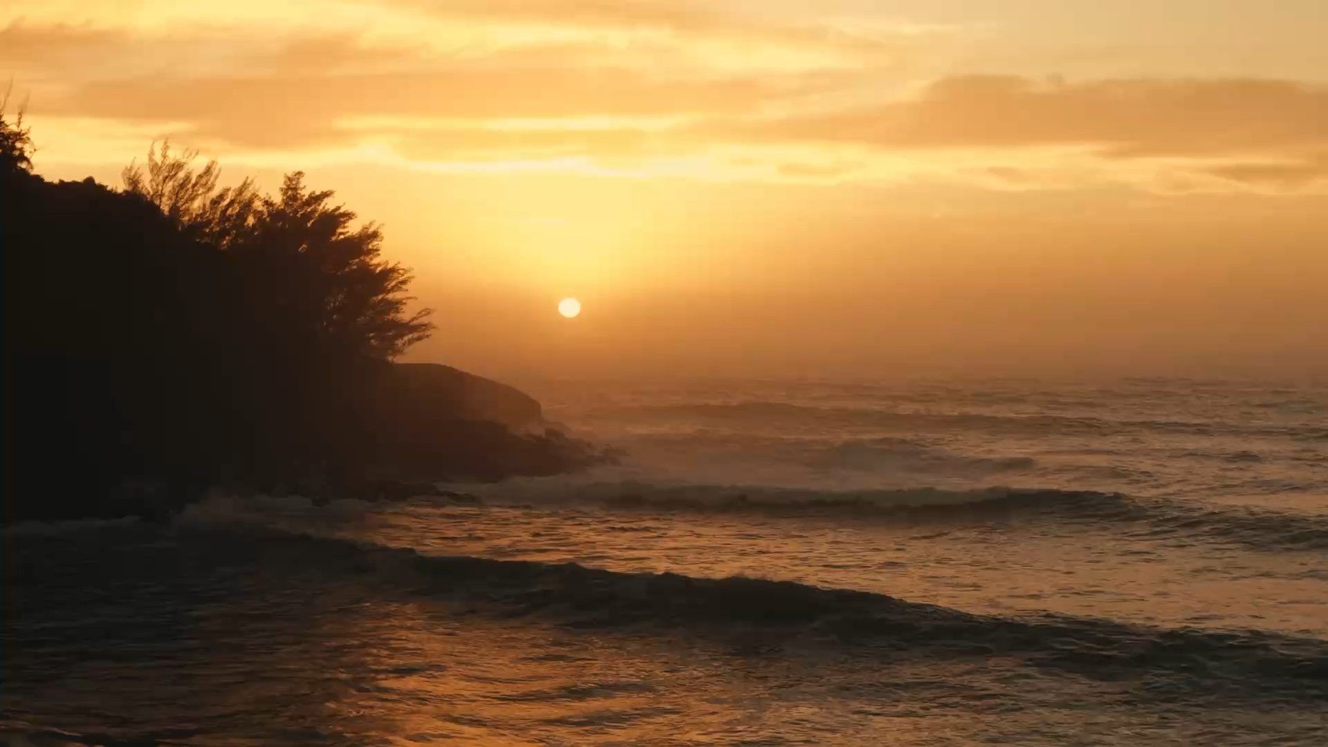 Amanecer sobre el mar en Ferrugem, con la silueta de la selva y las olas