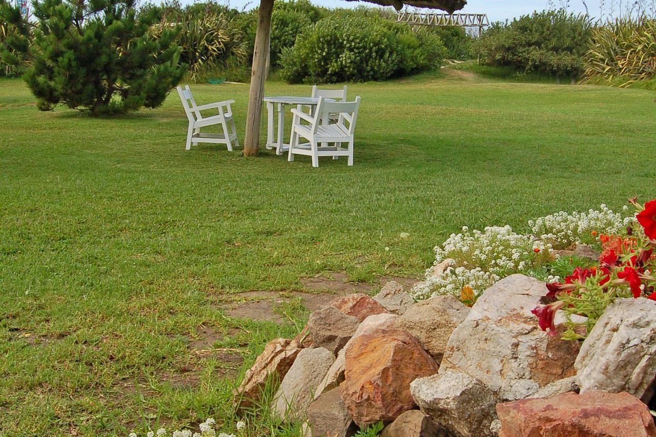 Jardín con sombrilla de paja y vista al mar en Portobello Suites