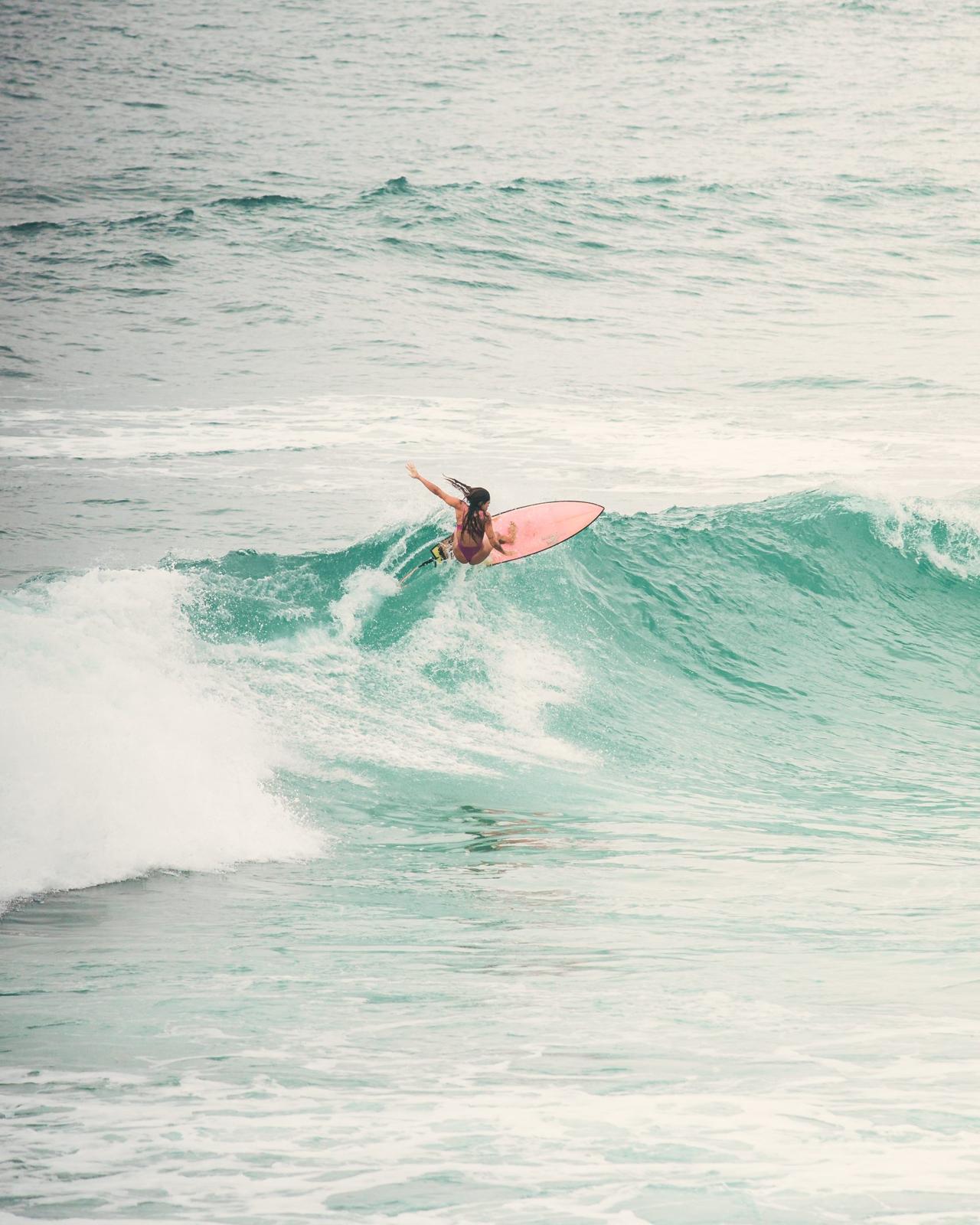 Surfista con tabla rosa en una ola de Santa Catarina