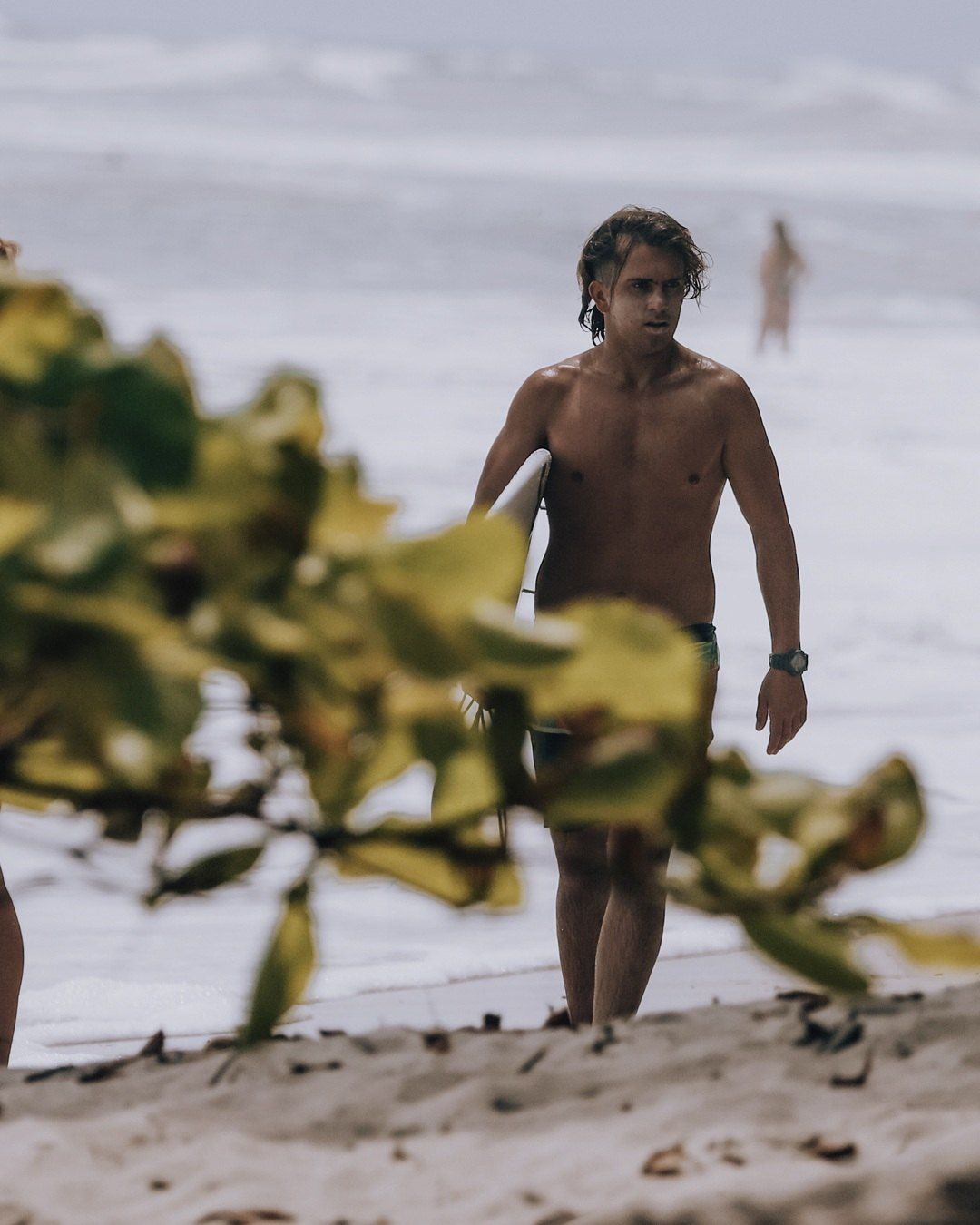 Ignacio Silva caminando por la playa con su tabla de surf