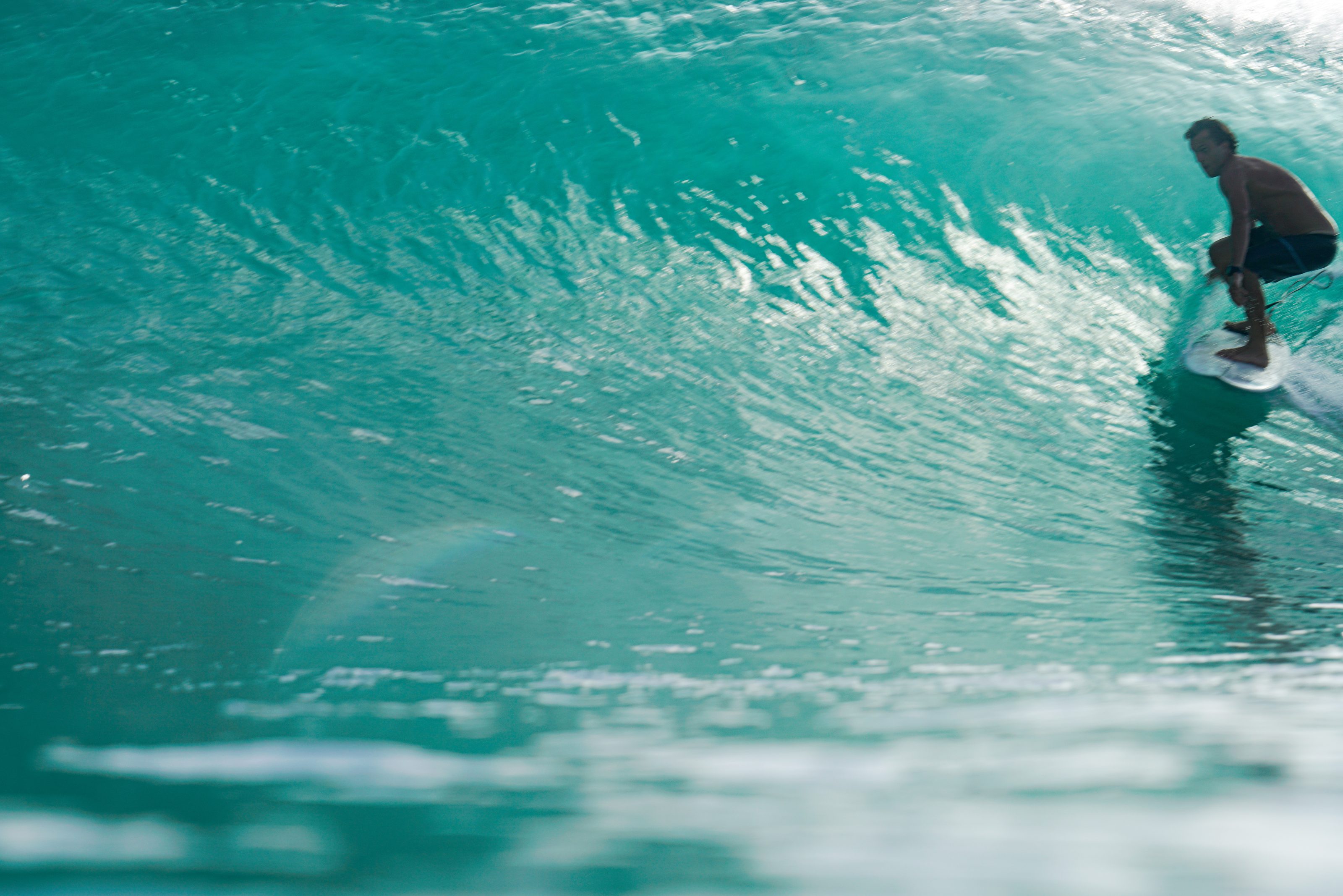 Surfista dentro de un tubo de agua turquesa en Nicaragua