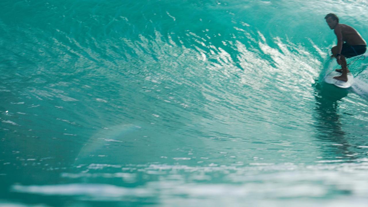 Surfista dentro de un tubo de agua turquesa en Nicaragua