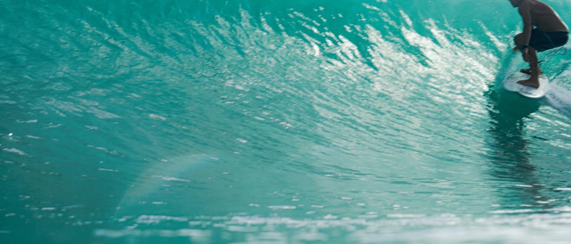 Surfista dentro de un tubo de agua turquesa en Nicaragua