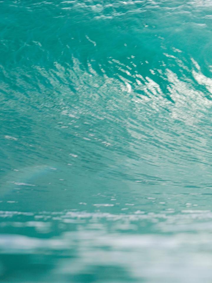 Surfista dentro de un tubo de agua turquesa en Nicaragua