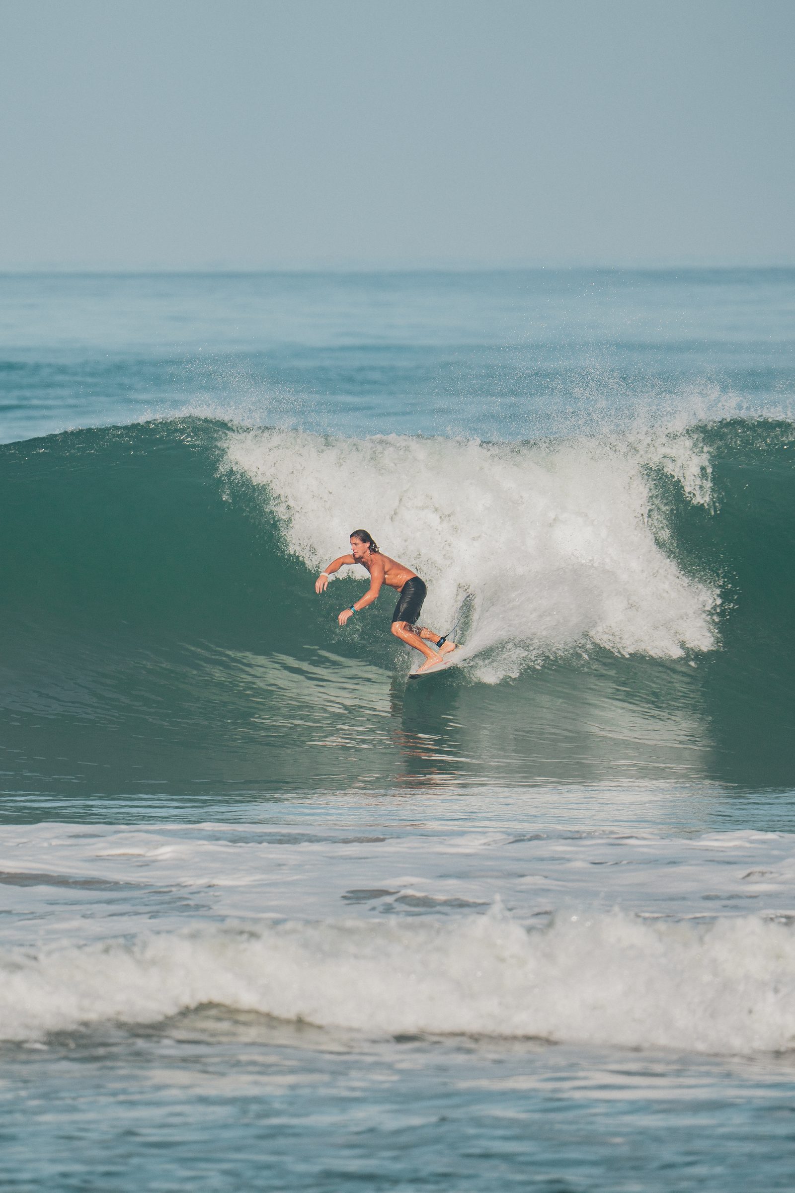Surfista en la pared de la ola, con la espuma rompiendo atrás