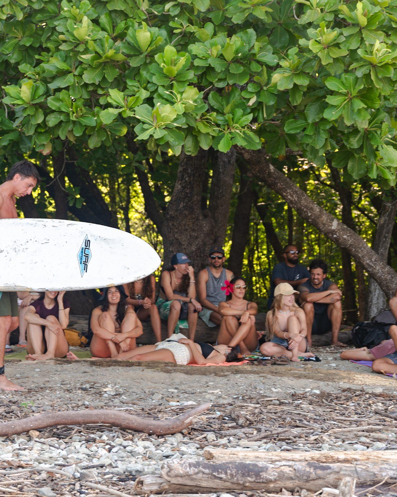 El grupo descansando a la sombra en la playa, con las tablas