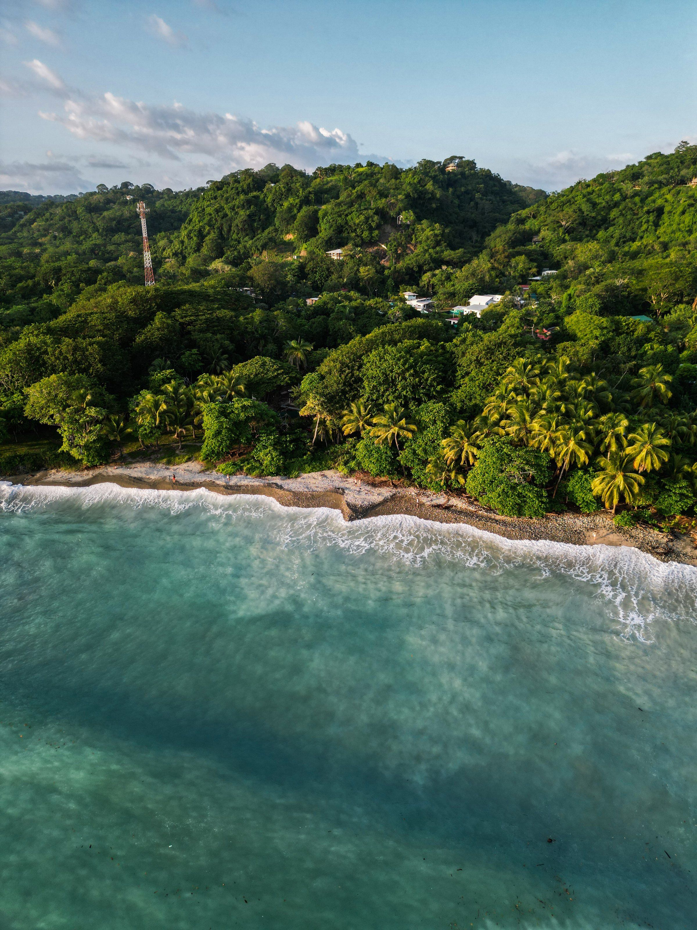 Costa del Pacífico de Costa Rica desde el aire, con cerros cubiertos de selva y el mar verde azulado