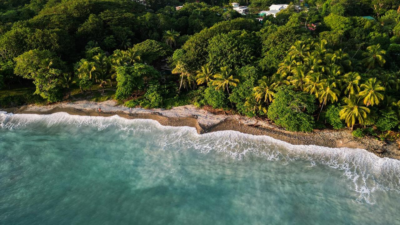 Costa del Pacífico de Costa Rica desde el aire, con cerros cubiertos de selva y el mar verde azulado