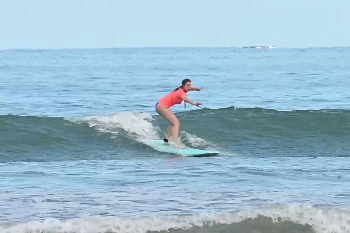 Principiante parada en su tabla corriendo una ola en Costa Rica