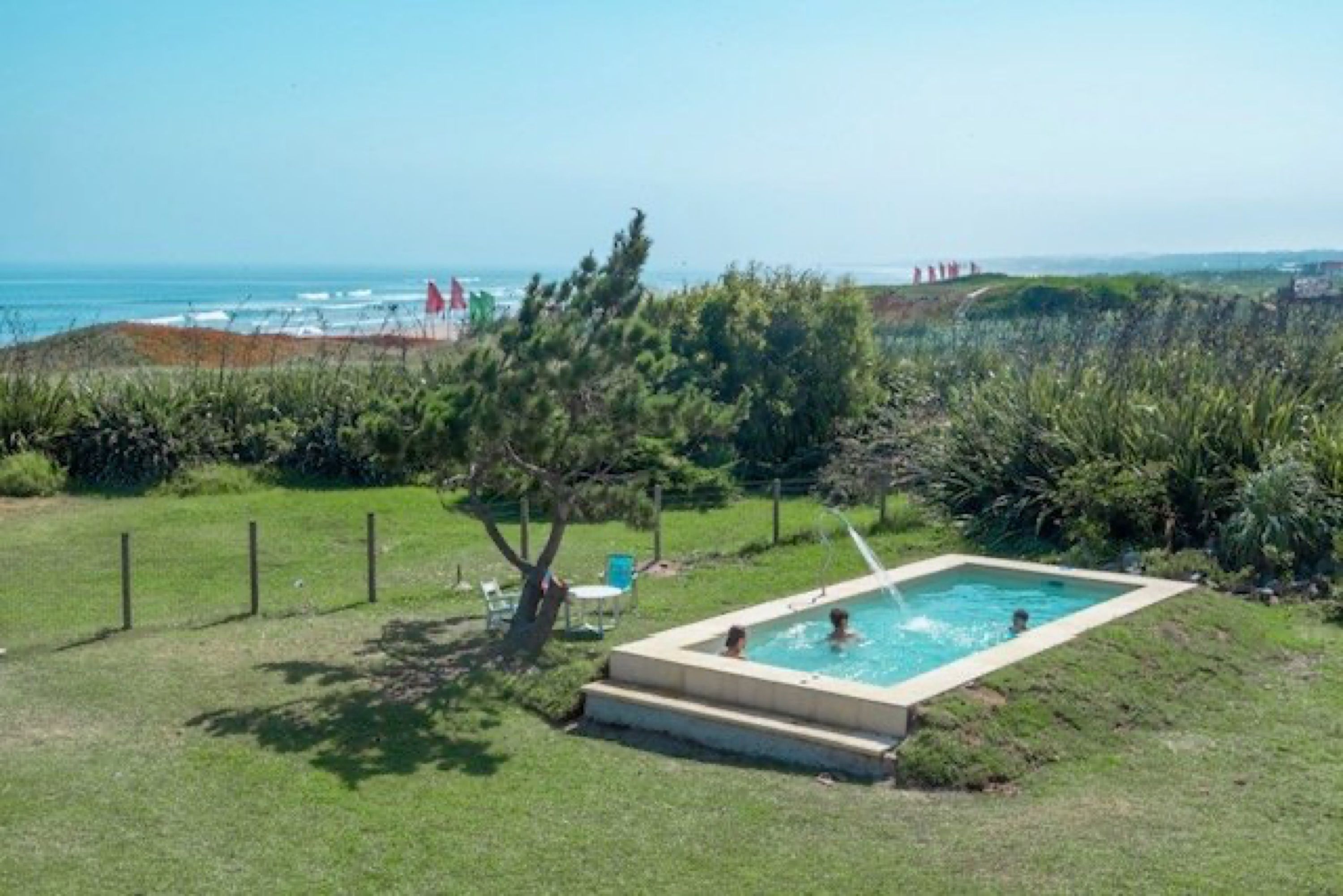 Piscina en el jardín de Portobello Suites, con el mar de fondo