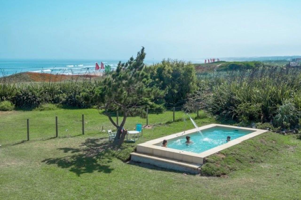 Piscina en el jardín de Portobello Suites, con el mar de fondo