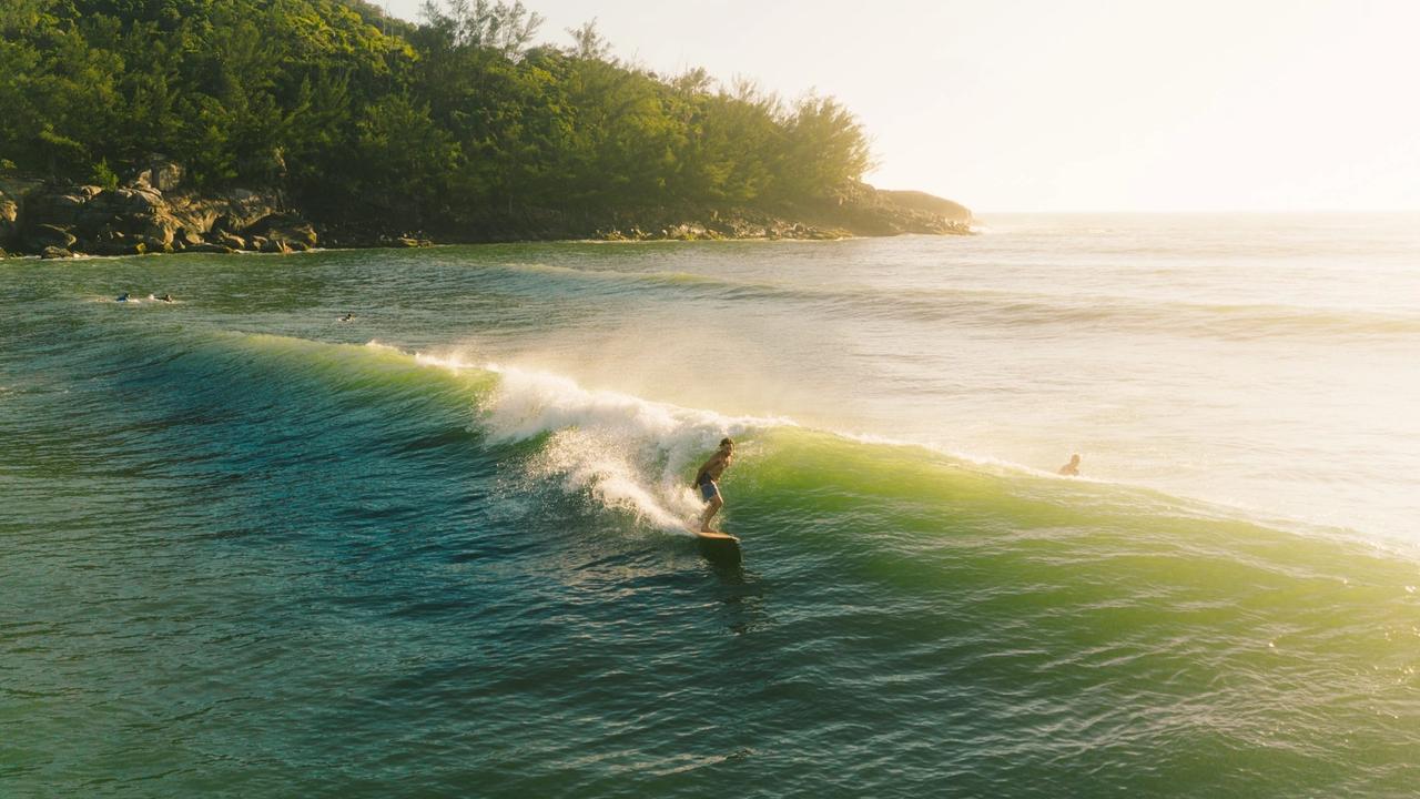 Surfista en una ola al amanecer en Ferrugem, Santa Catarina