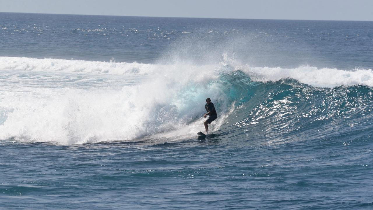 Surfista en una ola turquesa en Maldivas