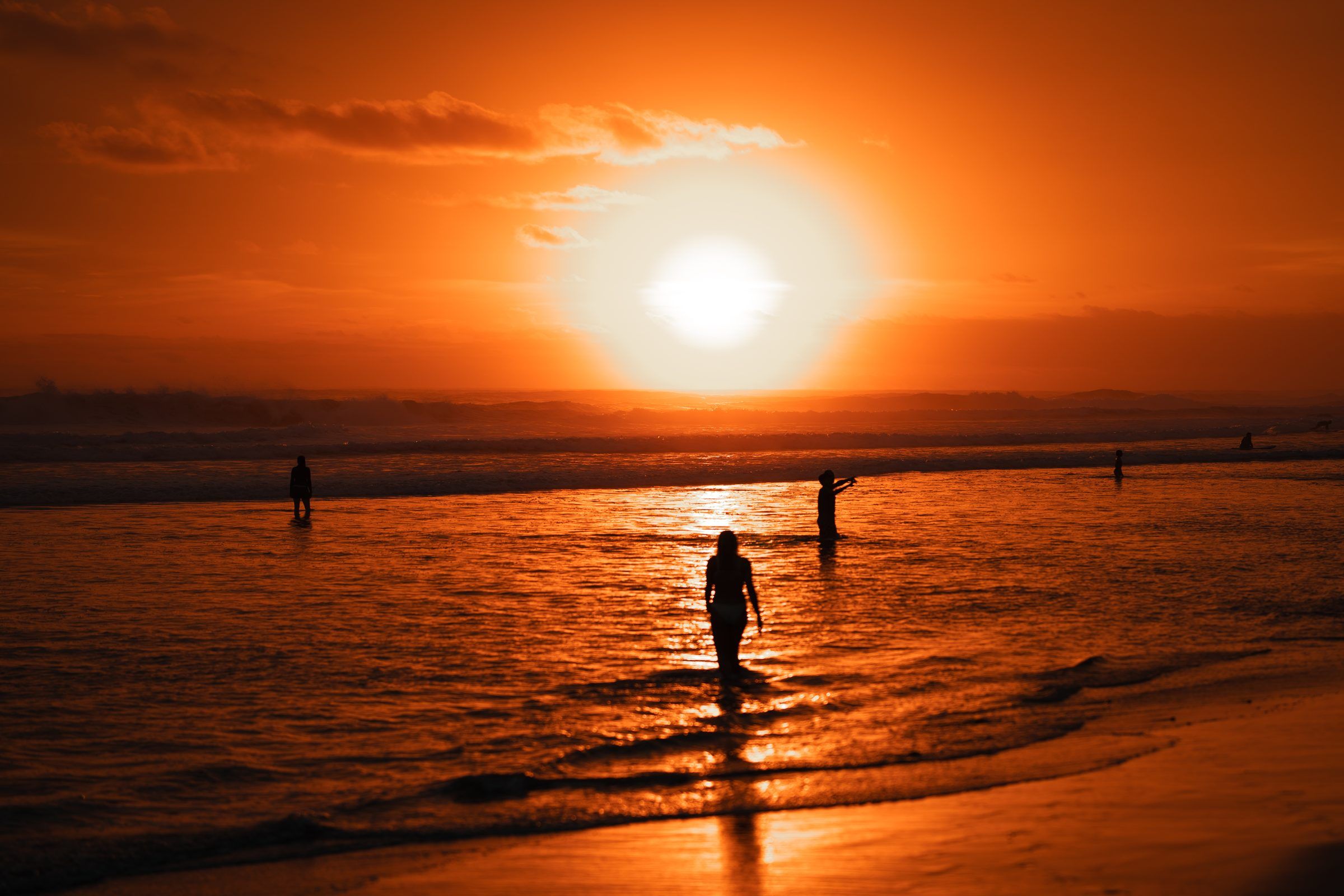 Atardecer naranja sobre el Pacífico con gente en la orilla