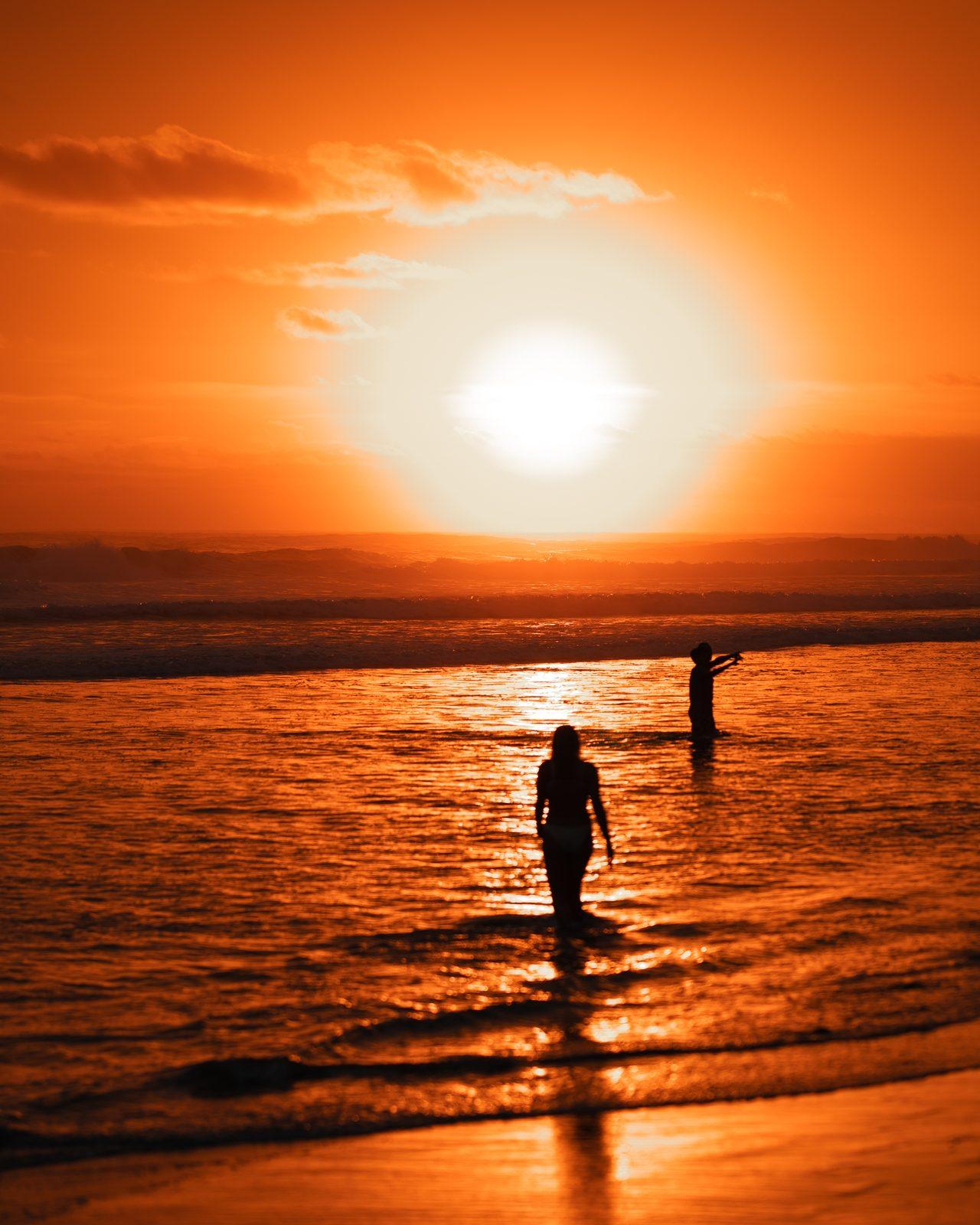 Atardecer naranja sobre el Pacífico con gente en la orilla