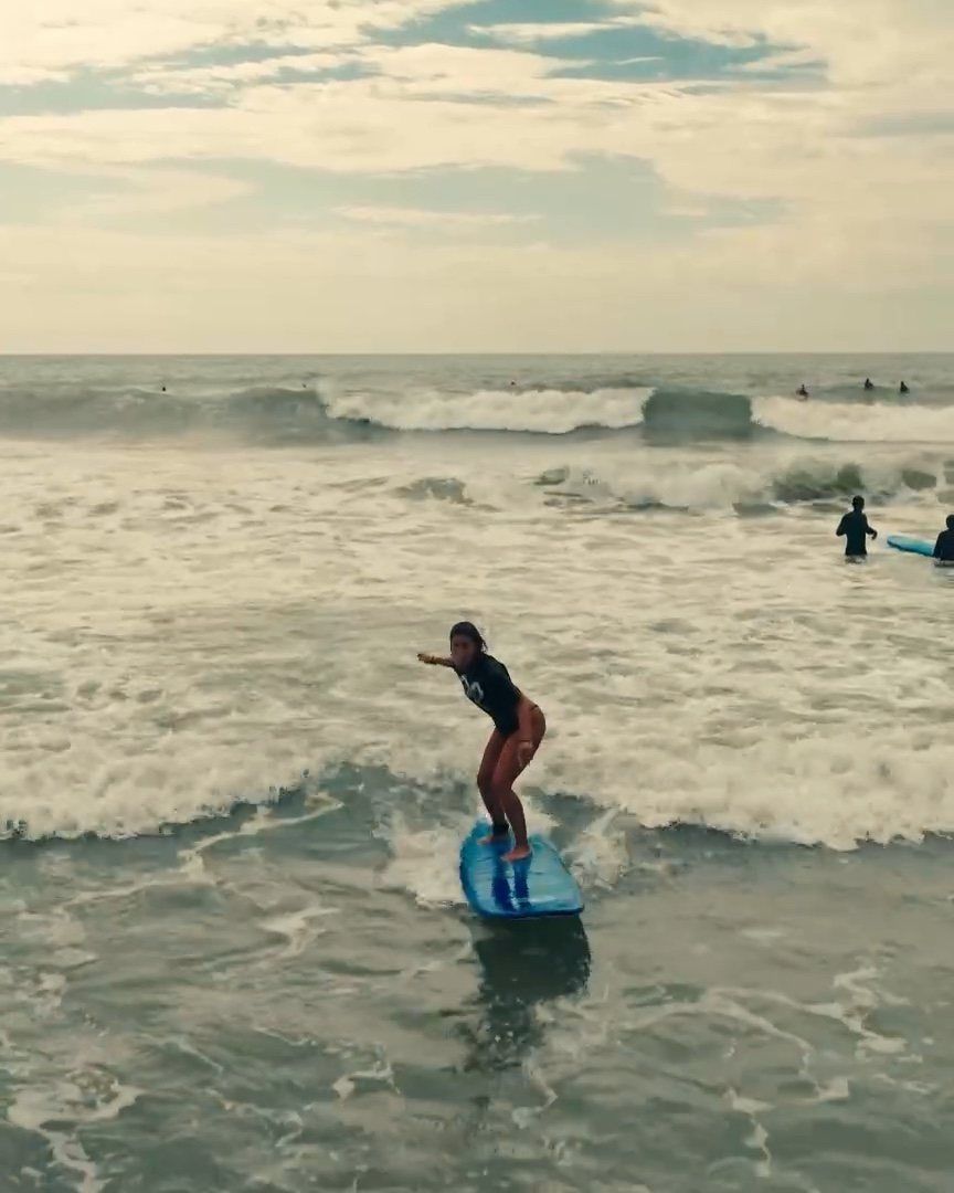 Principiante parada en su tabla en una clase de surf en Brasil