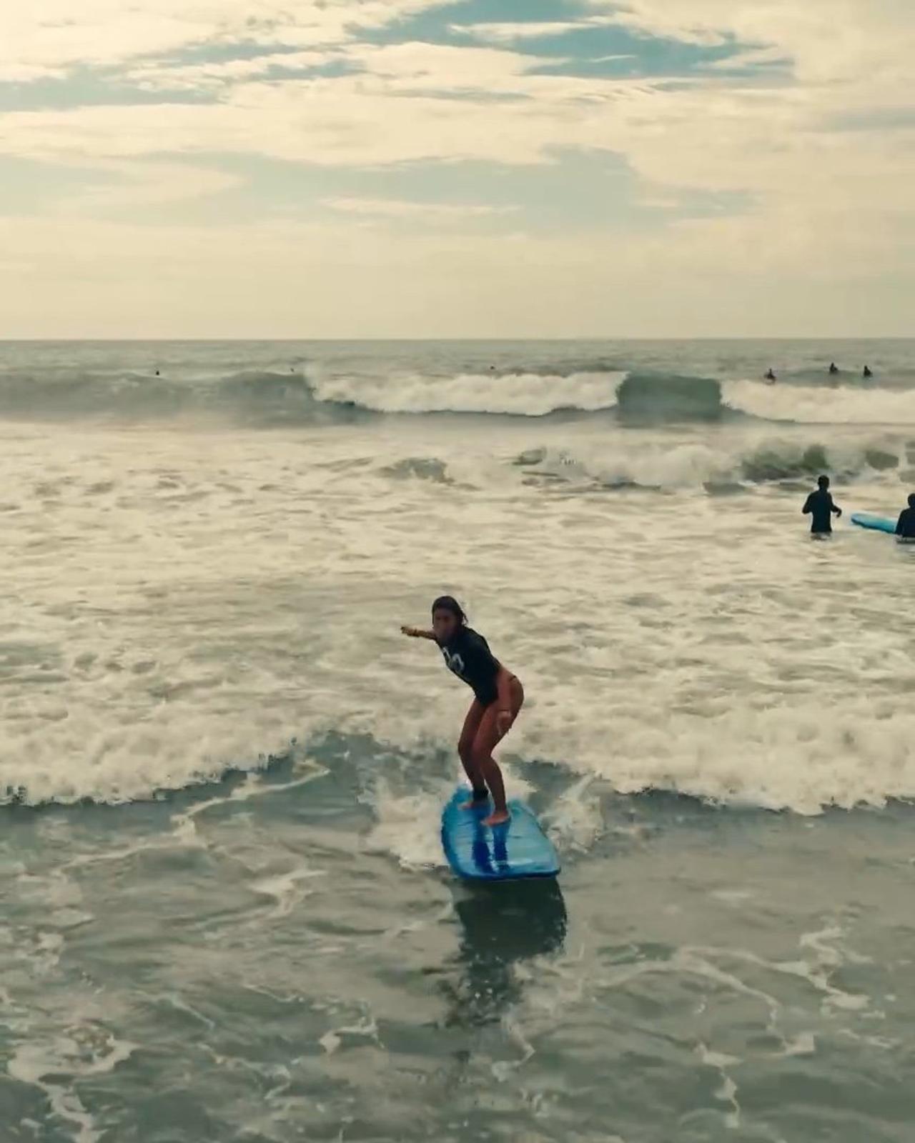 Principiante parada en su tabla en una clase de surf en Brasil