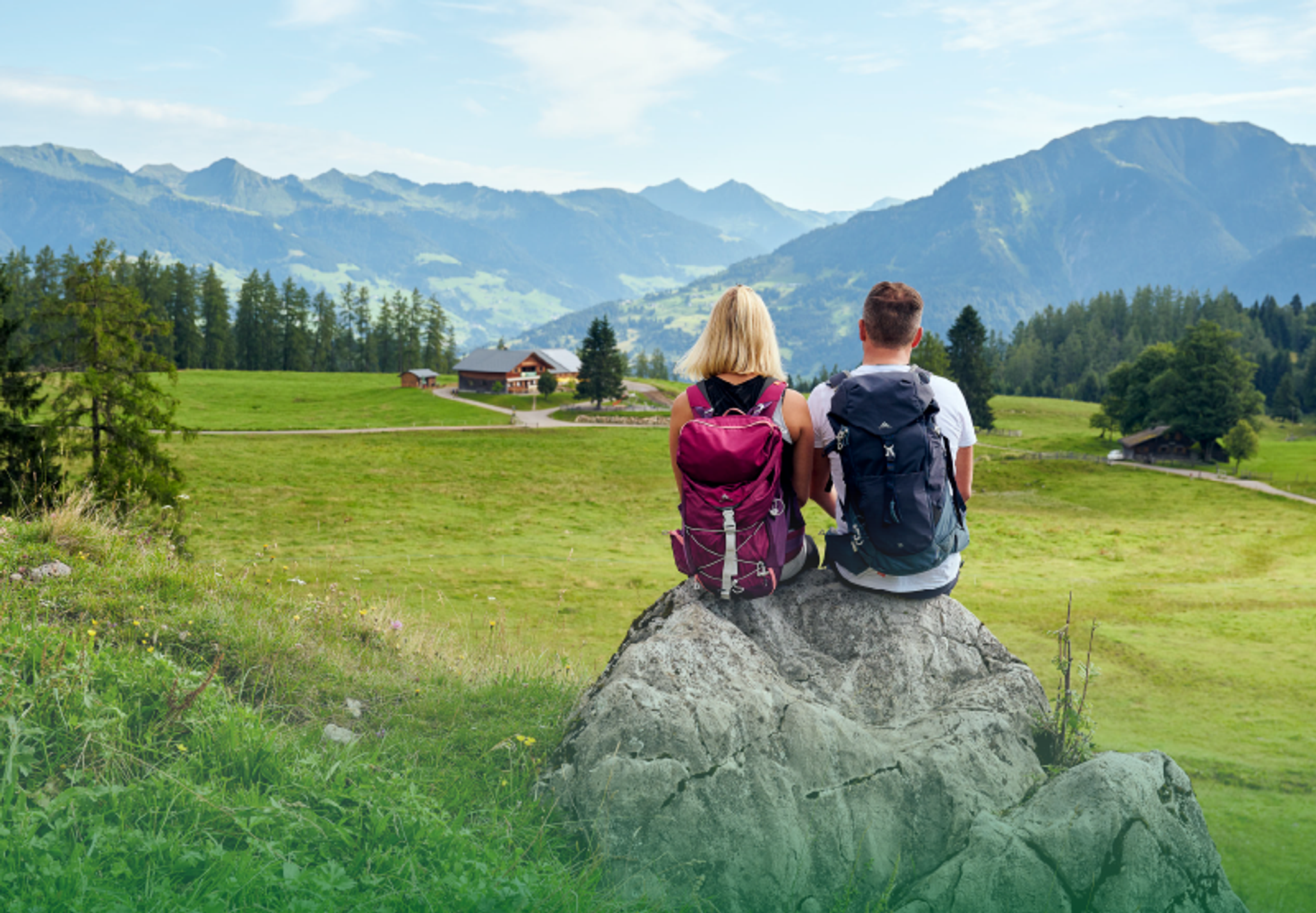 Ein Paar sitzt auf einem großen Stein und genießt das Panorama