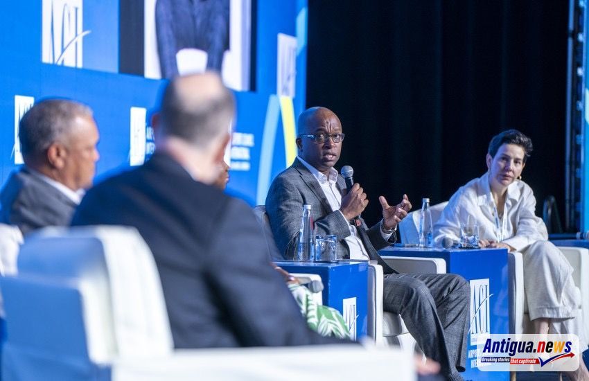 Mr. Kurt Menal, Chief Executive Officer of V.C. Bird International Airport, addresses the audience while participating in a panel discussion. Menal is pictured holding a microphone and engaging with fellow panellists during the session.
