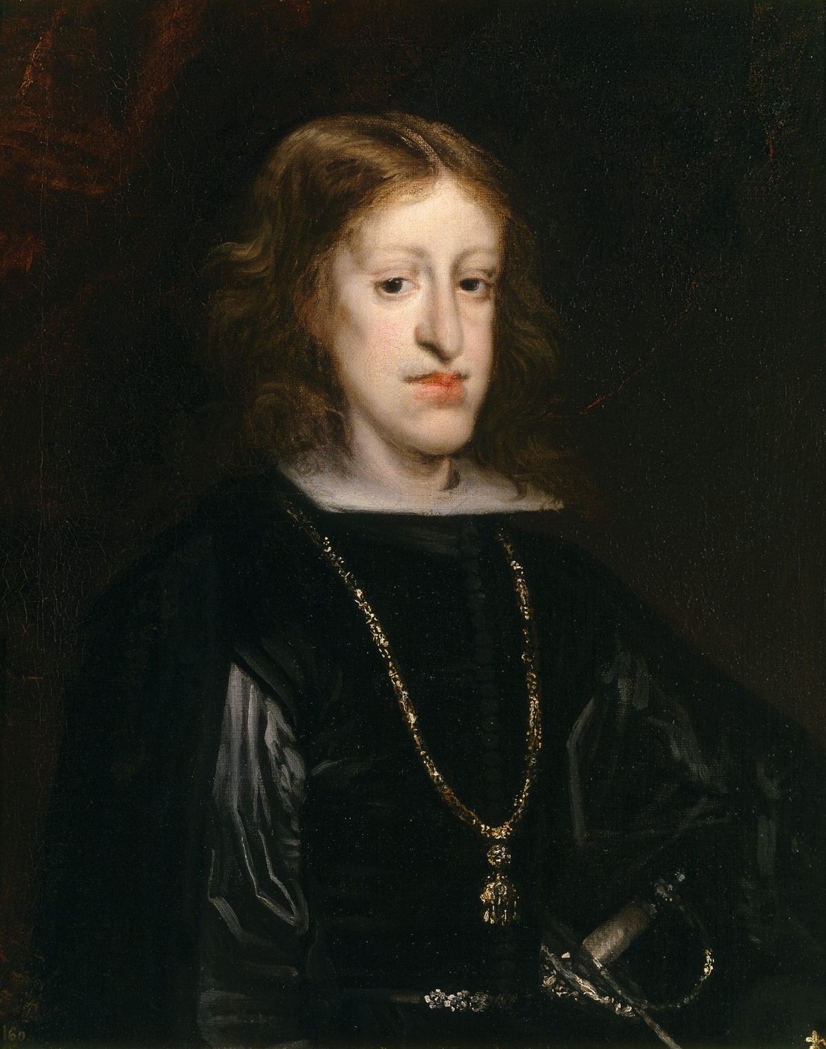 Portrait of a pale young man with long wavy hair, a dark coat and a gold chain.