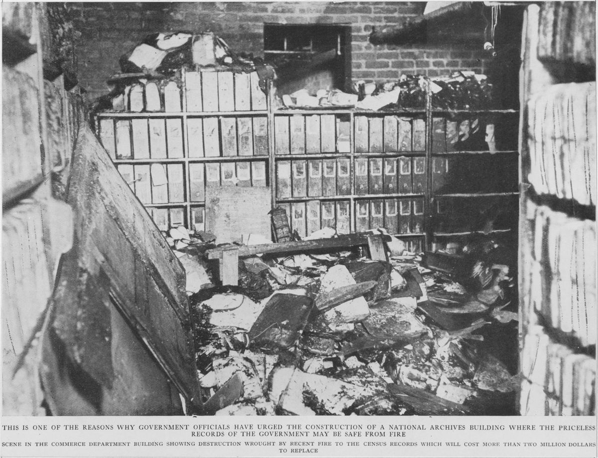 A black-and-white photograph of a burned records room with scorched binders on shelves.
