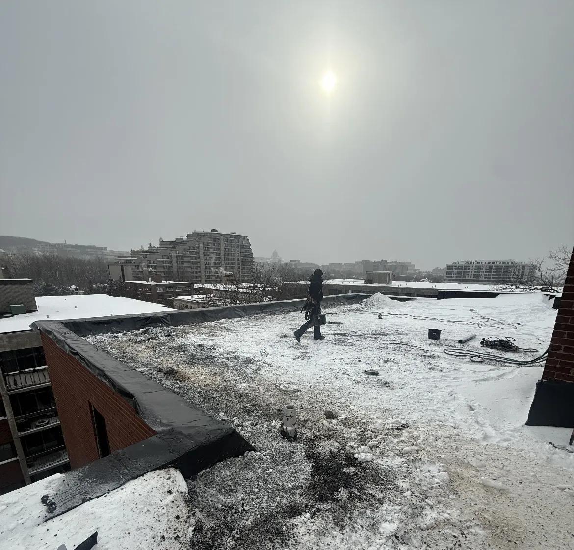 Couvreur professionnel lors d'une inspection hivernale de toiture pour urgence